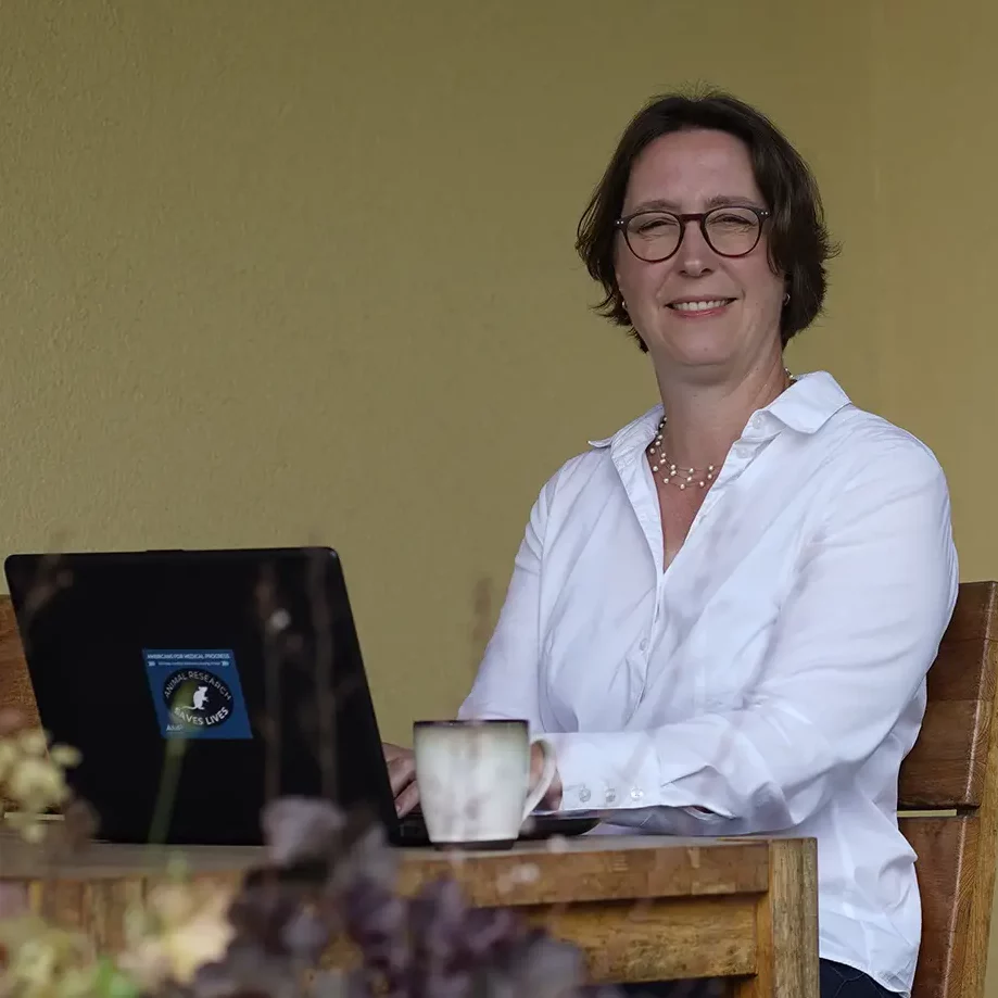 Stefanie Flunkert sitzt mit Laptop an einem Garten-Tisch