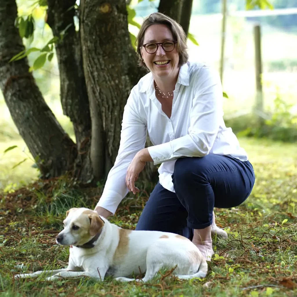 Stefanie Flunkert mit ihrem Hund im Garten vor einem Baum