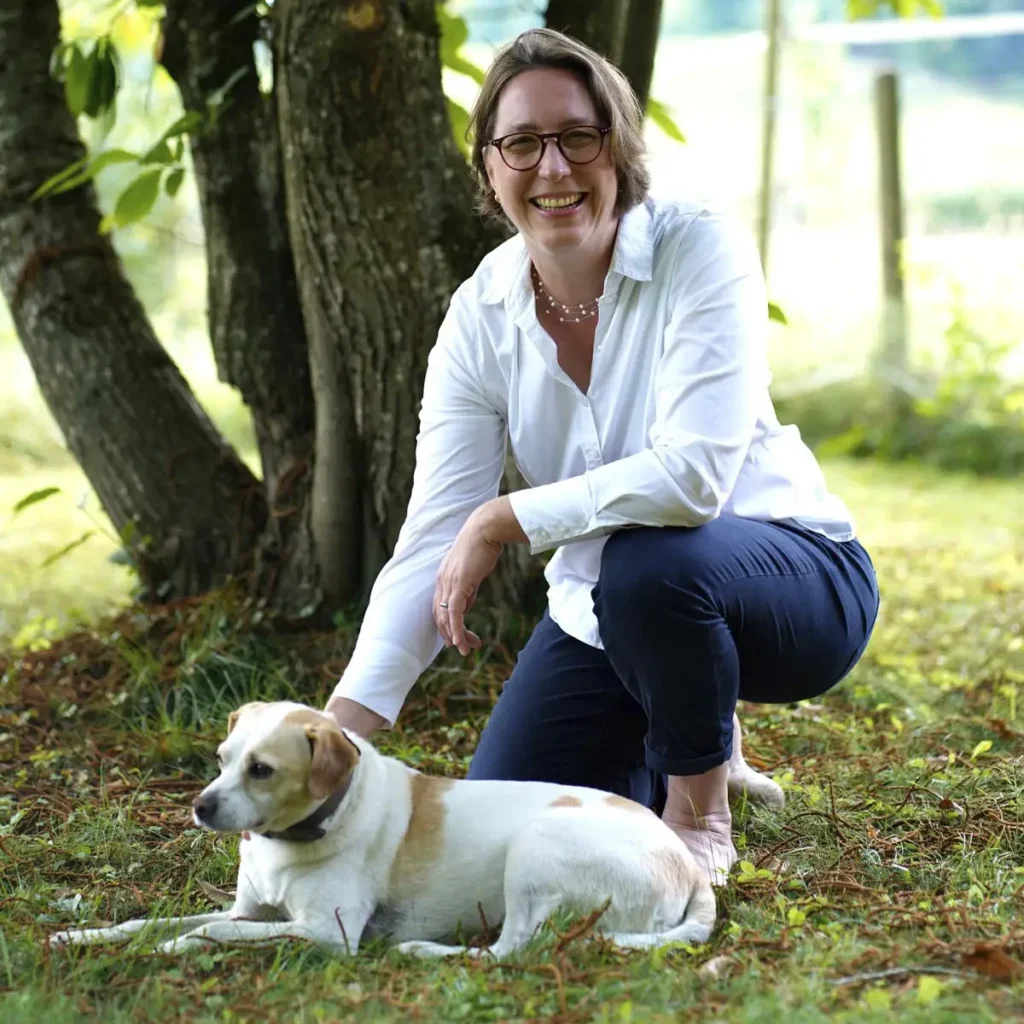 Stefanie Flunkert with her dog in the garden in front of a tree