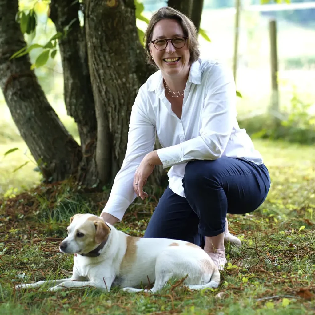 Stefanie Flunkert with her dog in the garden in front of a tree