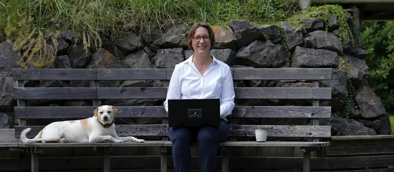 Stefanie Flunkert with her dog and laptop on a garden bench