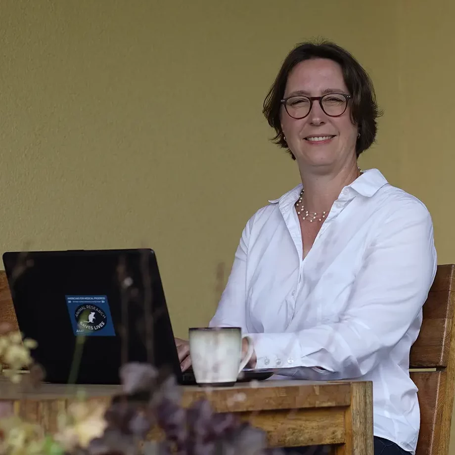 Stefanie Flunkert sits at a garden table with a laptop