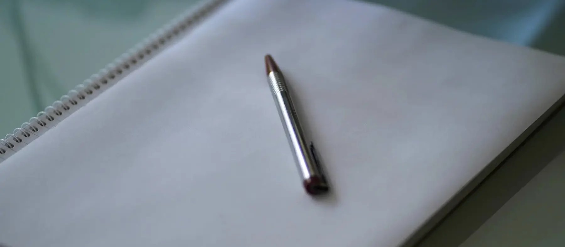 A silver ballpoint pen on a white notepad