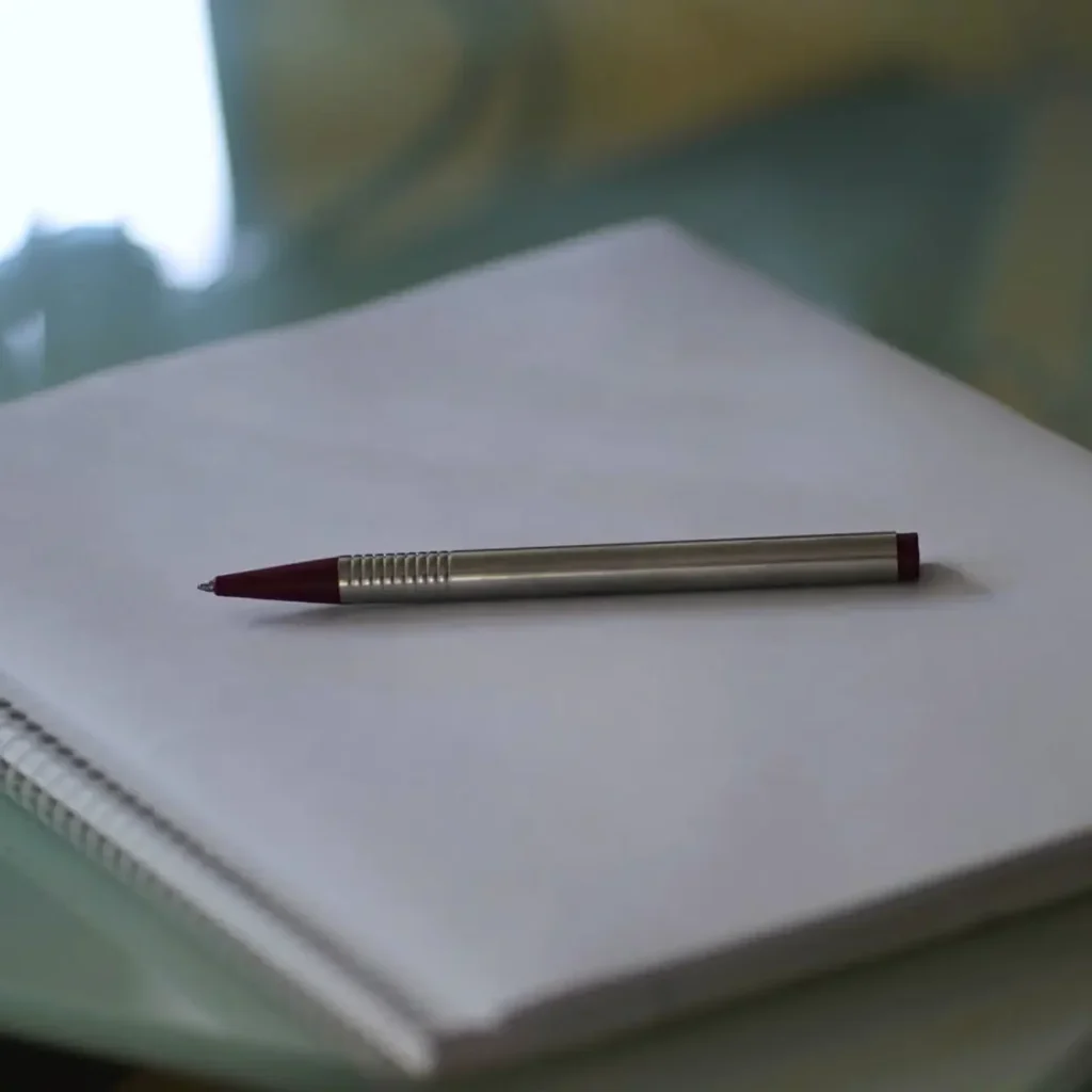 A silver ballpoint pen on a white notepad